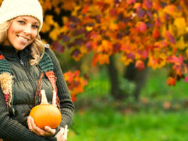 Young blonde woman holding a pumpkin in fall